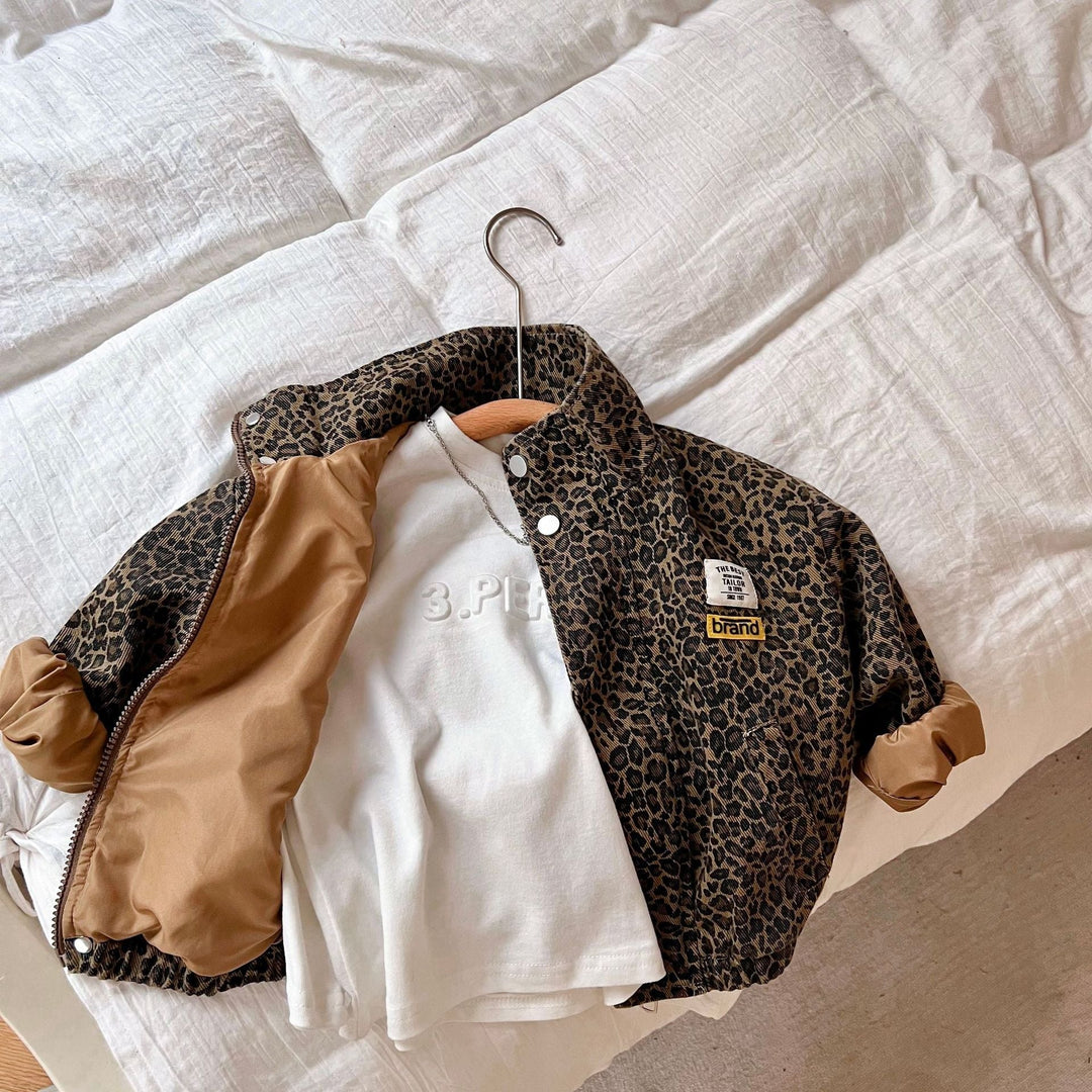 Open leopard print jacket showing tan lining, styled over a white shirt on bedding