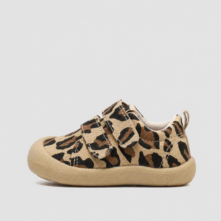 Side view of a leopard-print canvas sneaker with a tan sole and strap closure