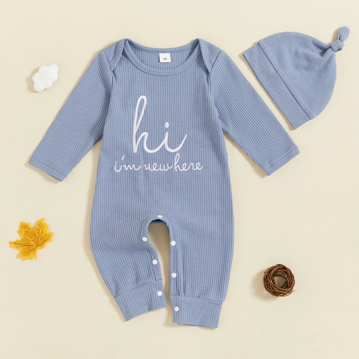 Light blue ribbed baby jumpsuit with white lettering, leg snaps and a matching knotted beanie
