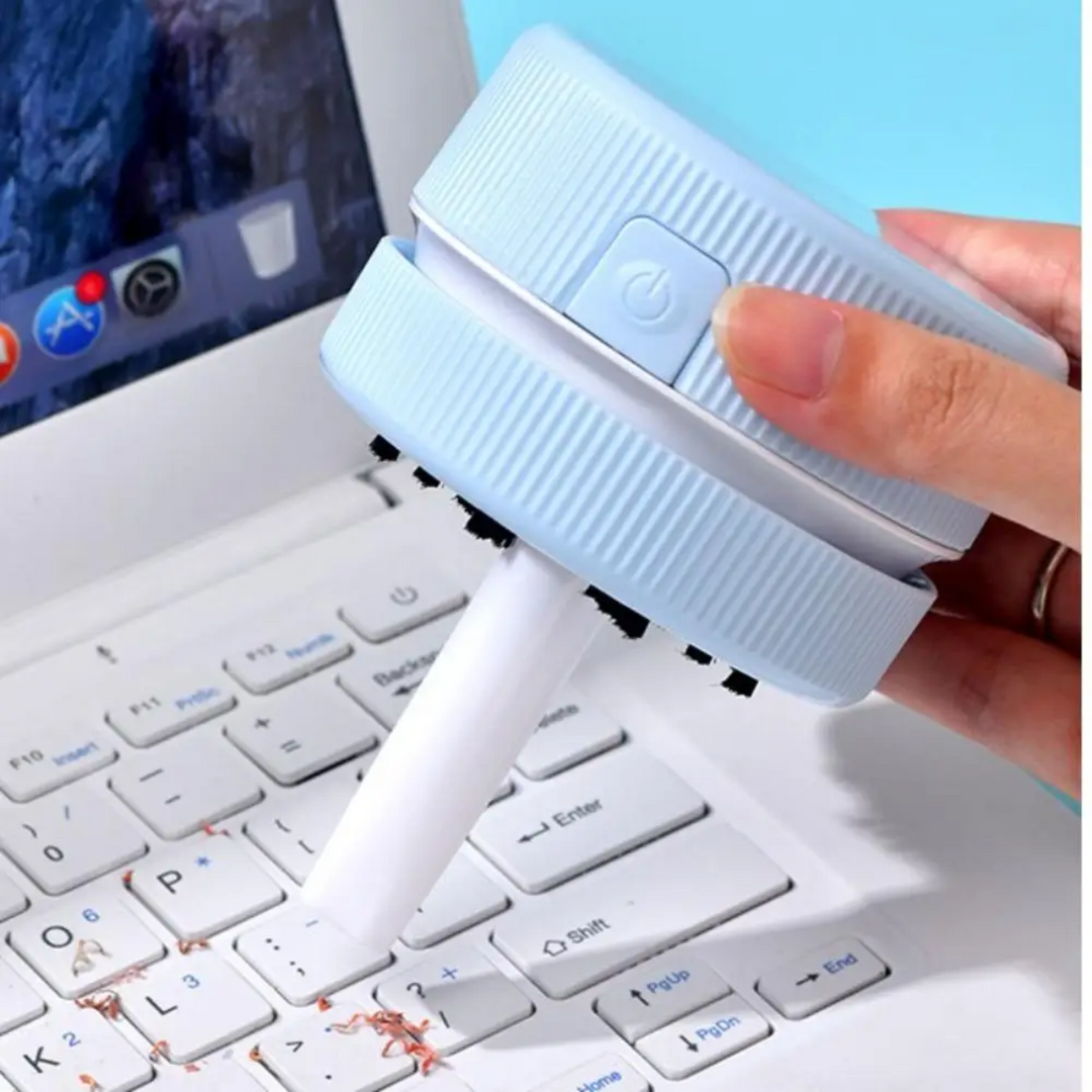Light blue desktop cleaner with a nozzle positioned over pencil shavings on a keyboard