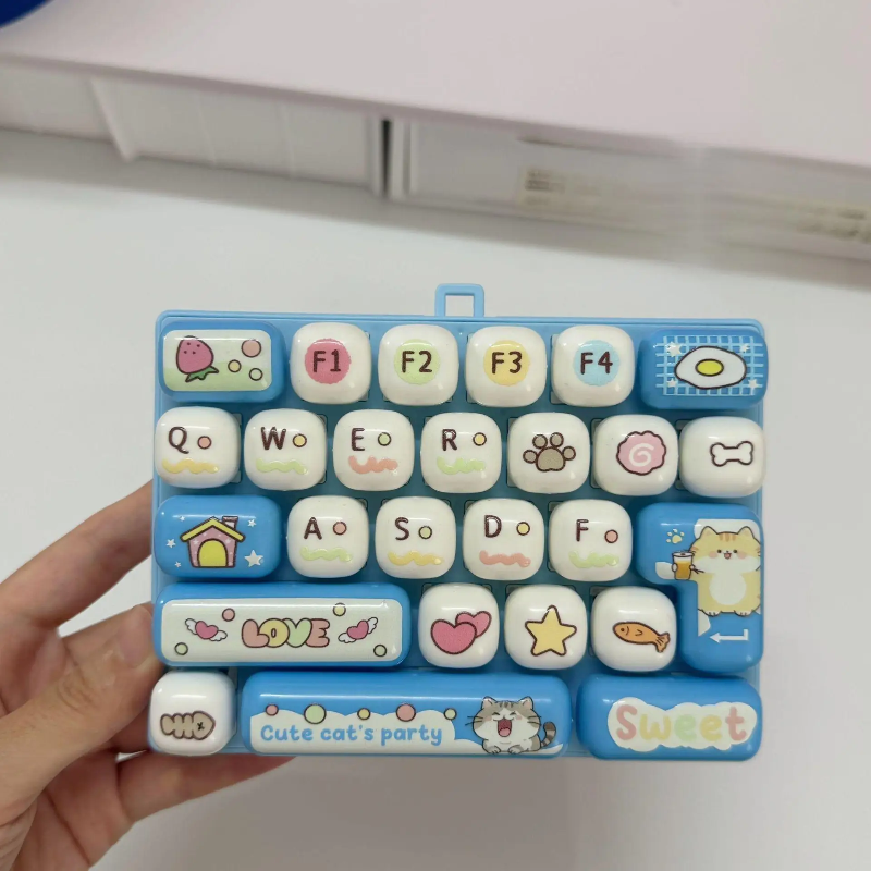 Light blue fidget keyboard held in one hand, showing its letter and picture keys
