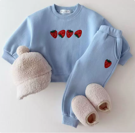 Light blue strawberry sweater and matching pants displayed with a knit hat and slippers