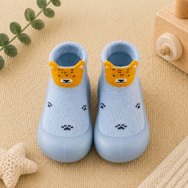 Light blue knitted sock shoes with tiger faces and paw-print patterns.
