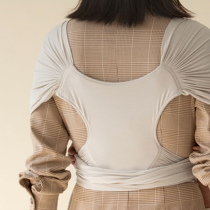 Rear view of a light gray baby carrier showing its broad fabric back panel and shoulder coverage