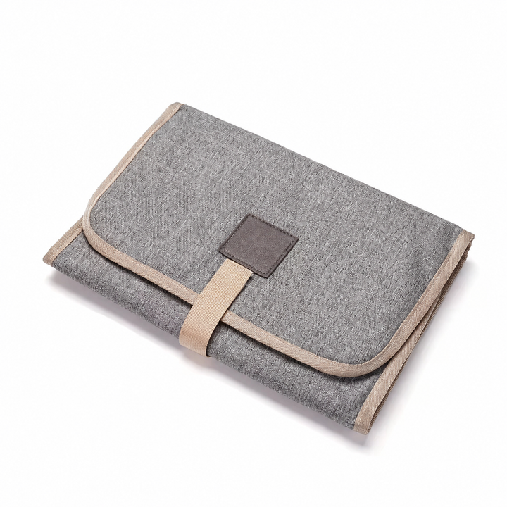 Light gray changing mat folded with a square patch and beige strap