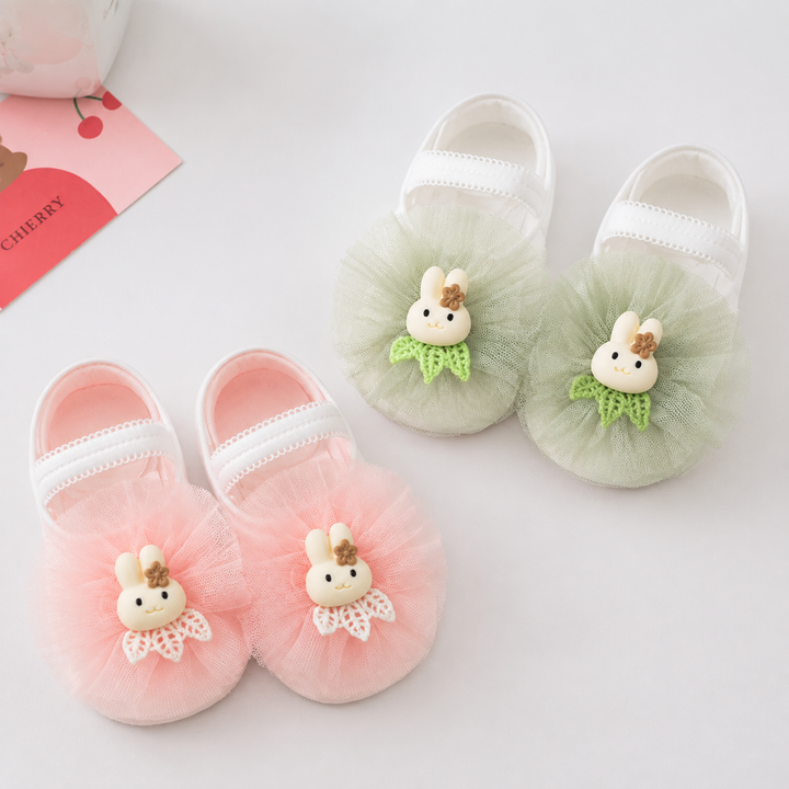 Light green and light pink baby socks with bunny accents and ruffled fronts