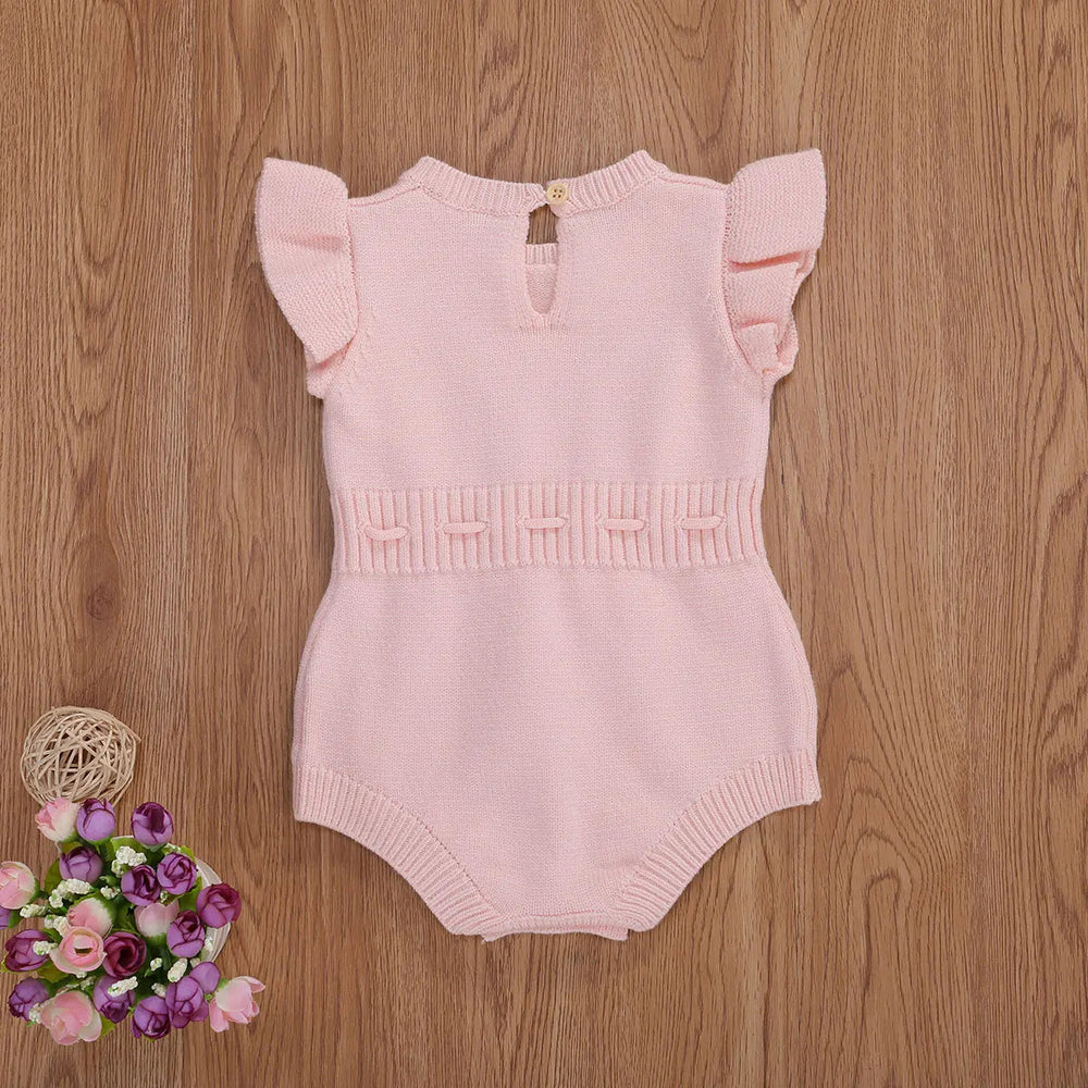 Light pink baby romper with ruffled shoulders and a buttoned back neckline