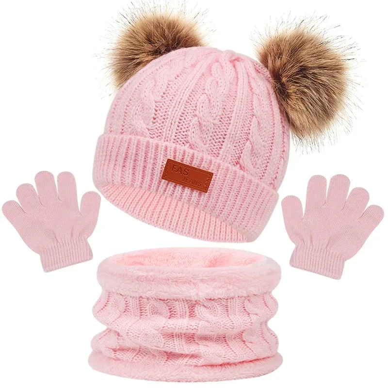 Light pink cable-knit winter set with a double-pom-pom hat, loop scarf, and gloves