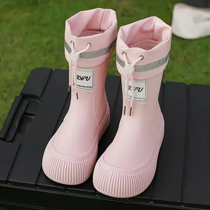 Light pink rain boots with drawstring cuffs displayed on a black slatted table