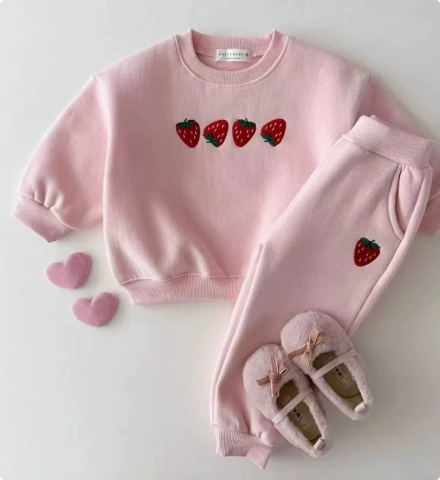 Light pink sweater and pants set with four strawberries on the chest and a strawberry on one leg