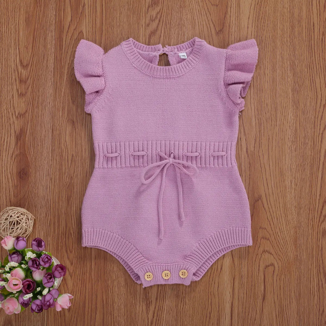 Light purple baby romper with ruffled sleeves, a waist bow, and leg buttons