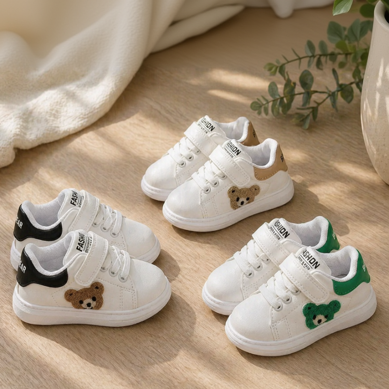 White bear-detail kids' sneakers in green, black, and beige accent options arranged on a wooden floor.