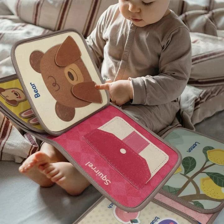 Child exploring a soft busy book with a bear activity and removable fruit pieces
