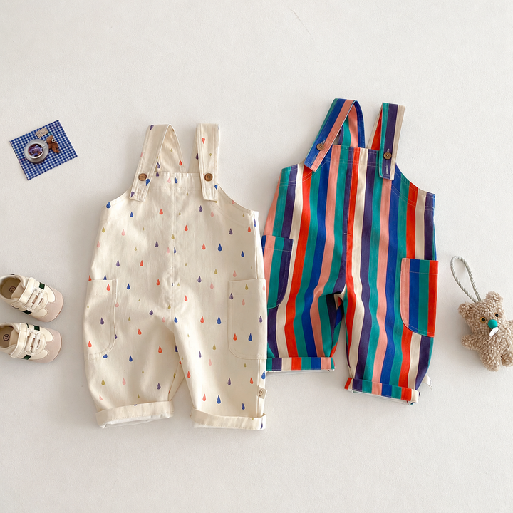 Cream raindrop and multicolored striped long overalls laid flat with buttoned shoulder straps