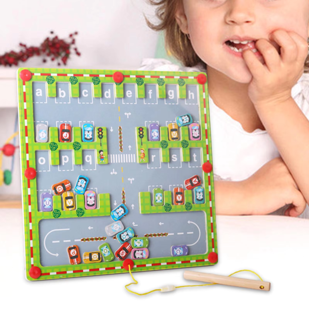 Child beside a magnetic alphabet board with lettered cars, parking spaces, and a corded pen