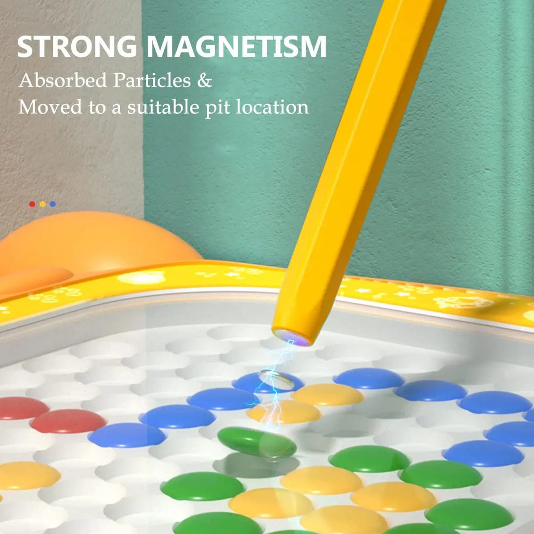 Close-up of a yellow magnetic pen lifting a green bead on the drawing board