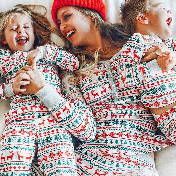 Mother and two children in matching red, green, and white Christmas pajamas