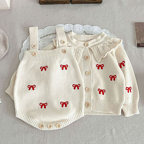 Matching white knit cardigan and bodysuit with red bow motifs laid flat