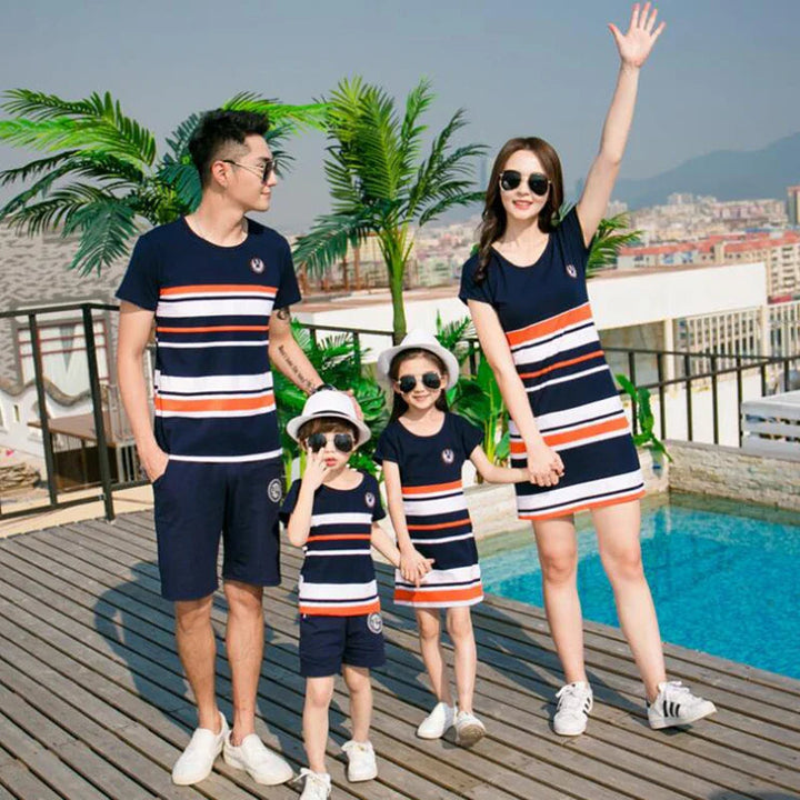 Family standing on a poolside deck in matching striped tees and dresses