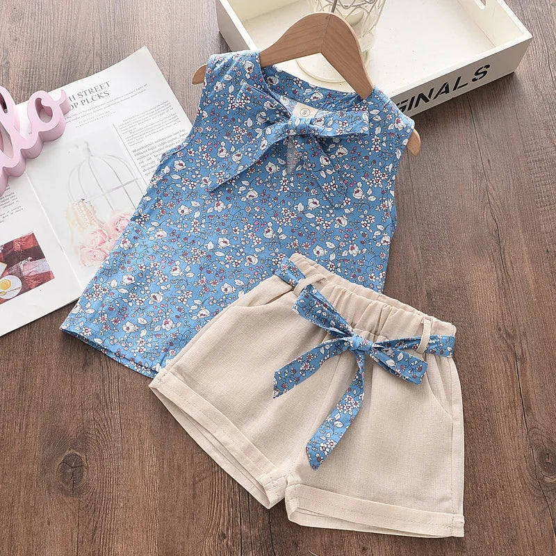 Blue floral sleeveless top with a neckline bow and beige shorts with a matching floral waist tie