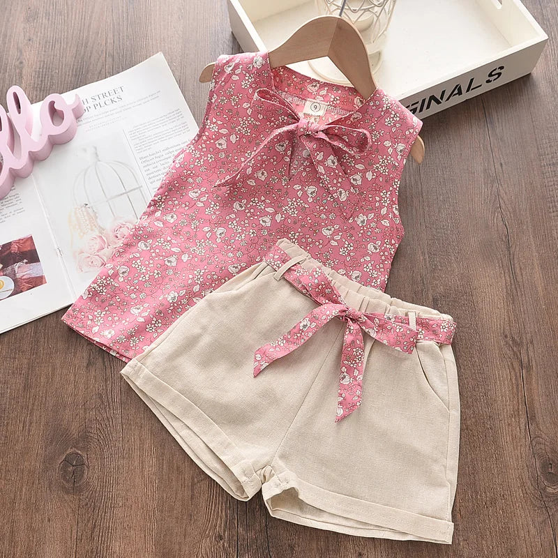 Pink floral sleeveless top paired with beige shorts and a pink floral waist tie