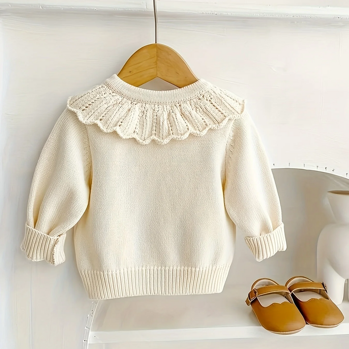 Back of the cream cardigan showing its ruffled collar and ribbed hem