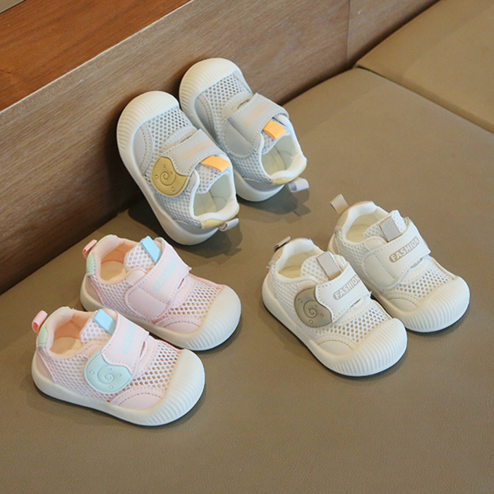 White, blue and pink mesh toddler sneakers arranged on a cushioned bench