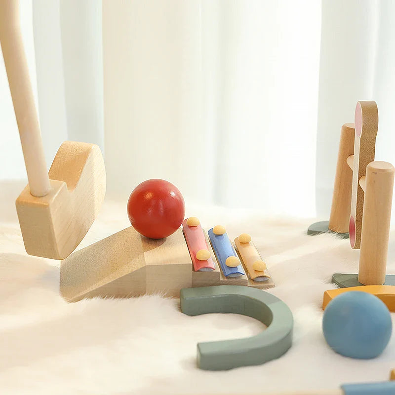 Red golf ball on a wooden ramp beside colored rails, a green arch and an upright obstacle