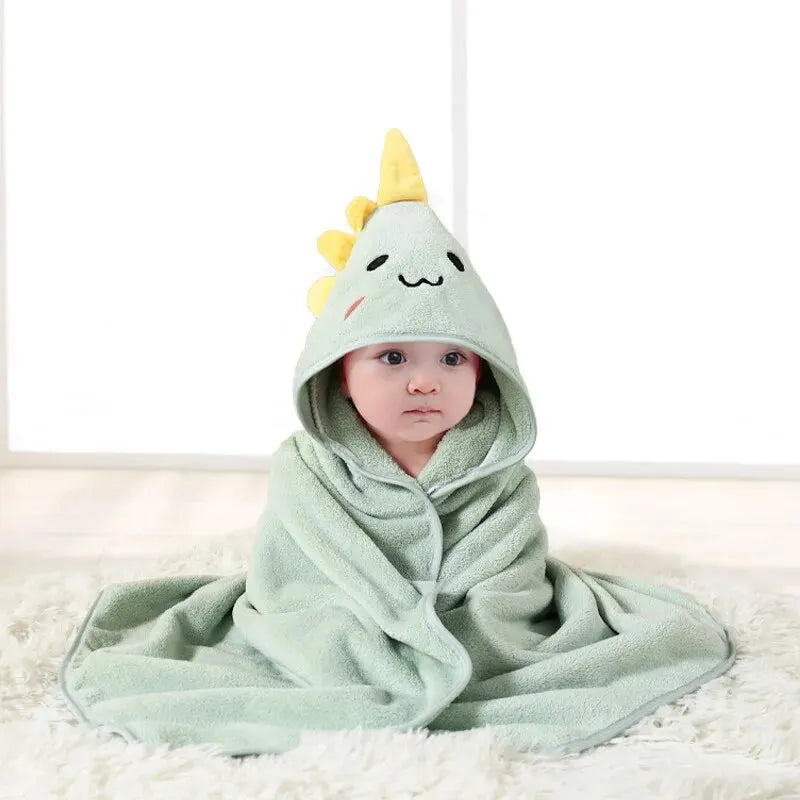 Child wrapped in a mint green dinosaur hooded bath towel with yellow spikes