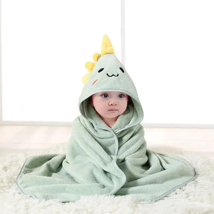 Child wrapped in a mint green dinosaur hooded bath towel with yellow spikes