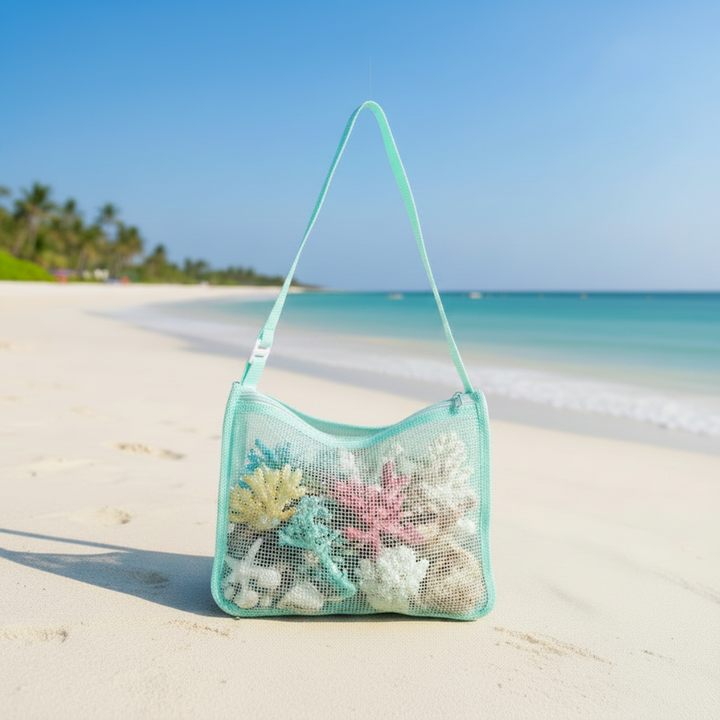 Mint green mesh shoulder bag holding seashells on a sandy beach