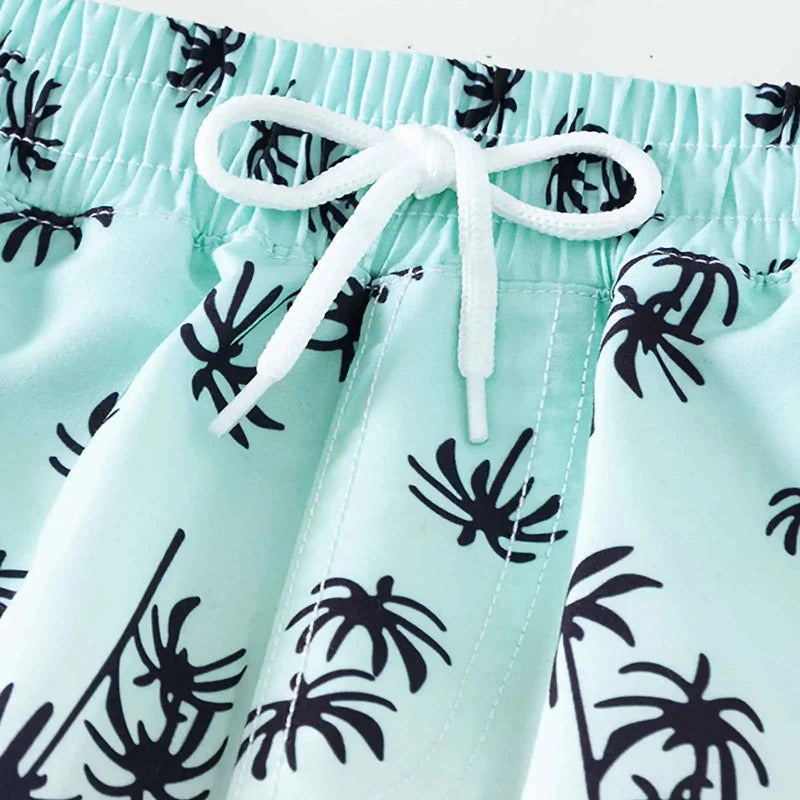 Close-up of the elastic waistband and white drawstring on mint palm-print swim trunks.