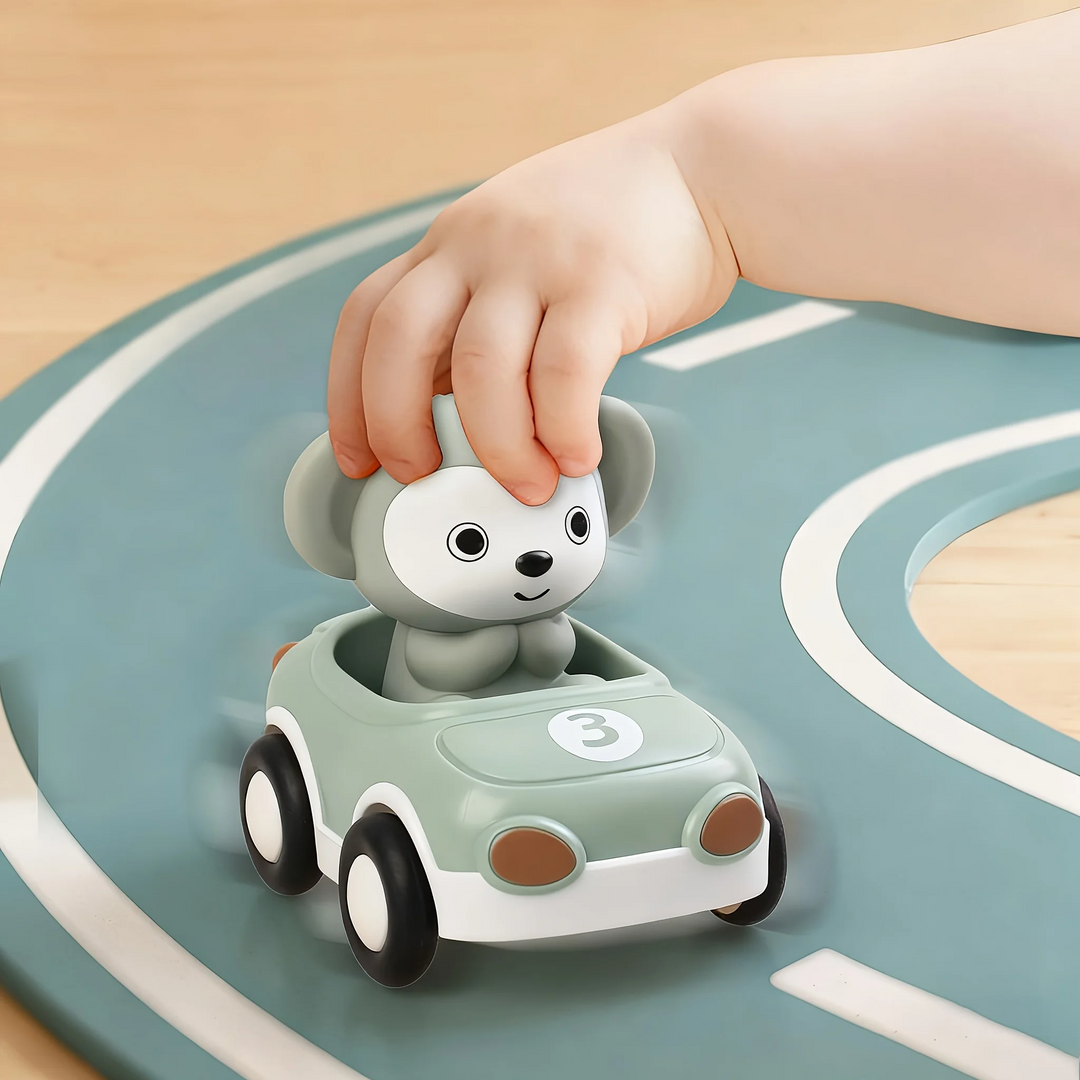 Hand pushing a green toy car with a monkey figure along a road mat