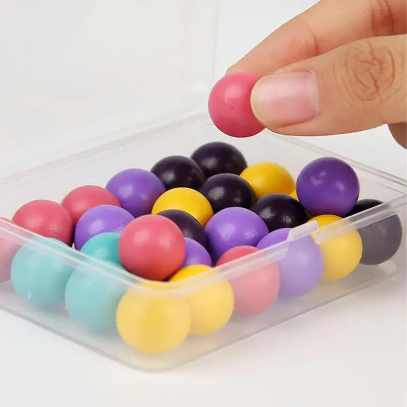 Hand holding a pink bead above a clear box of multicolored beads