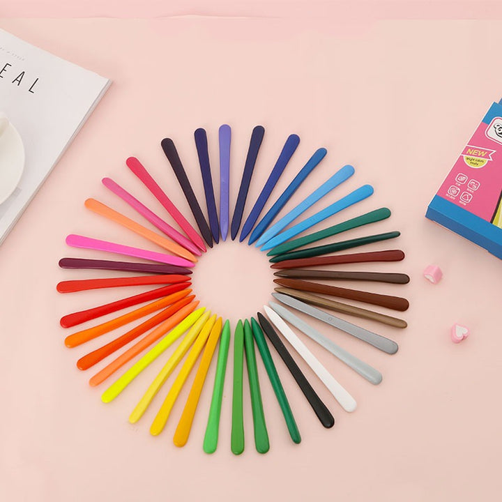 Multicolored slim crayons arranged in a circle on a pink surface