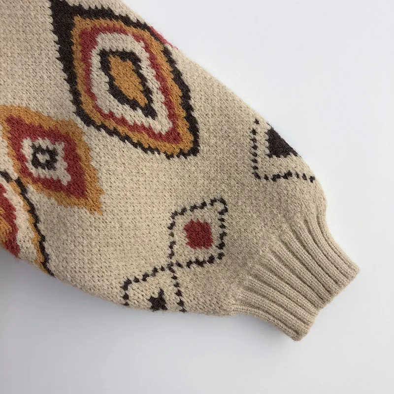 Red, yellow, and brown diamond details along a beige sweater sleeve with a ribbed cuff