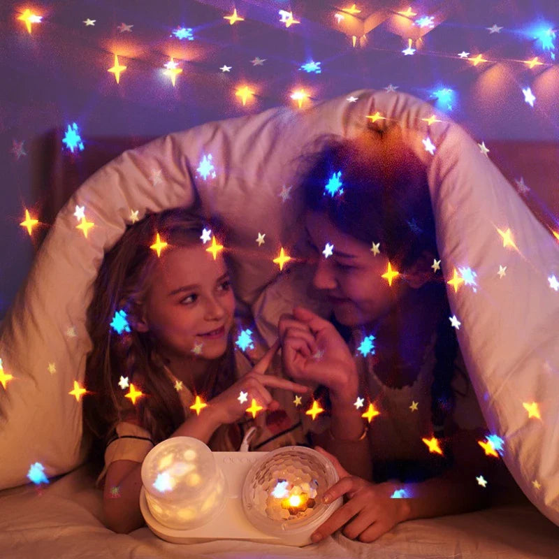A woman and child in a blanket fort lit by multicolored stars, with the night light in front.