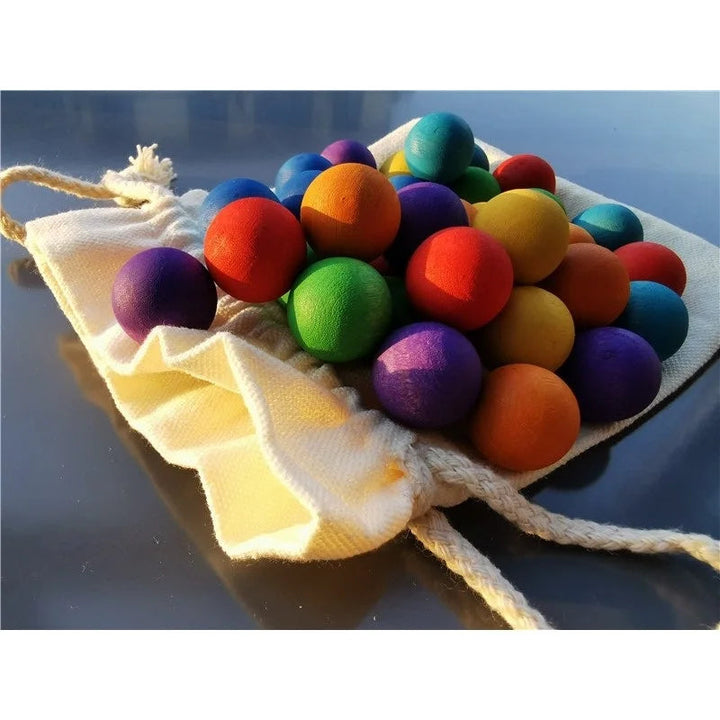 Bright wooden balls piled on an open cream drawstring bag