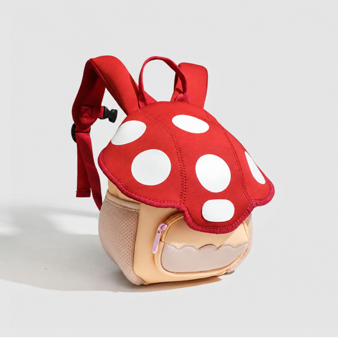Angled view of the Mushroom backpack showing its spotted red top, front zipper pocket, and mesh side pocket.