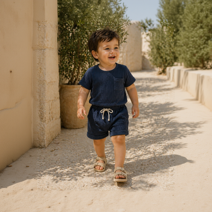 Child wearing a navy blue short-sleeve T-shirt and matching shorts on a sunny path.