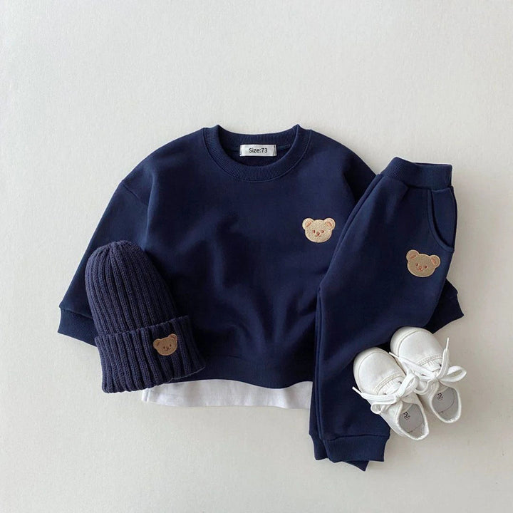 Navy blue bear-patch sweatshirt and pants styled with a ribbed hat and white shoes