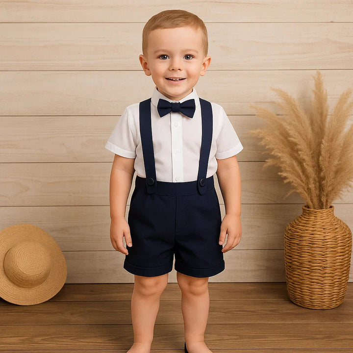 Boy wearing navy shorts, a white short-sleeve shirt, suspenders, and a matching bow tie