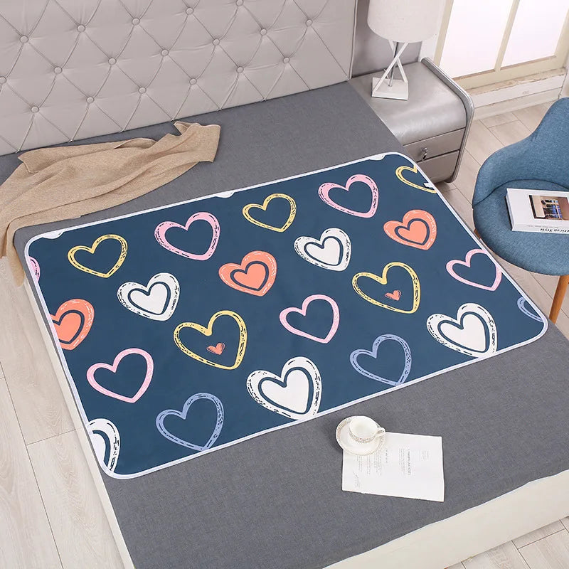 Navy changing mat with colorful outlined hearts spread across a gray bed.