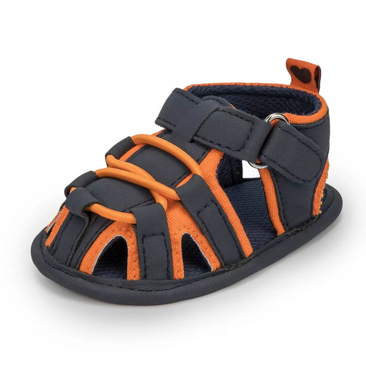 Navy baby sandal with orange trim, front cords and an ankle strap
