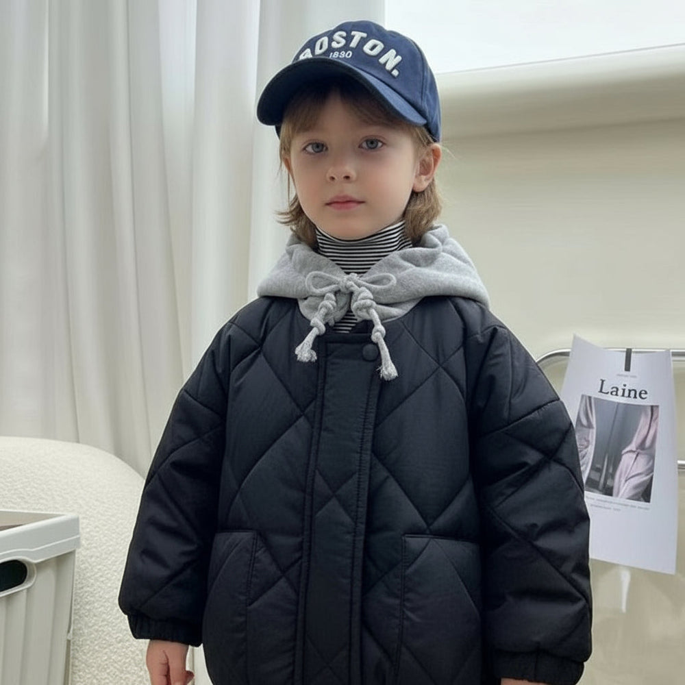 Child wearing a navy blue quilted jacket with a gray hood indoors.