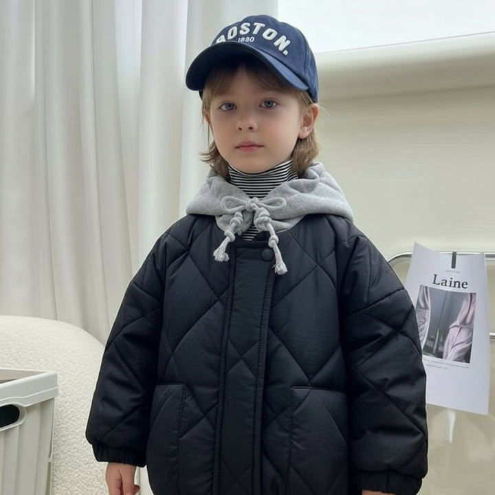 Child wearing a navy blue quilted jacket with a gray hood indoors.