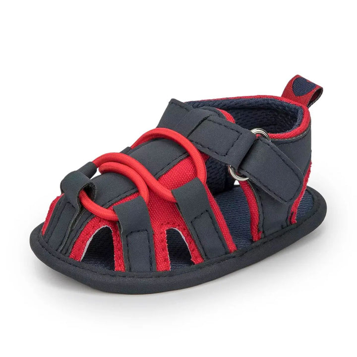 Navy baby sandal with red trim, front cords and an ankle strap