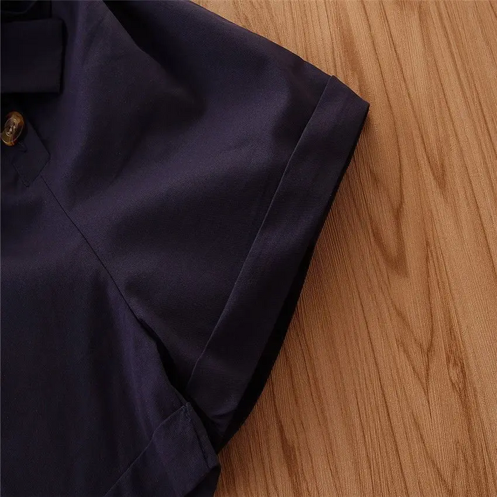 Folded sleeve cuff and seam detail on the navy romper