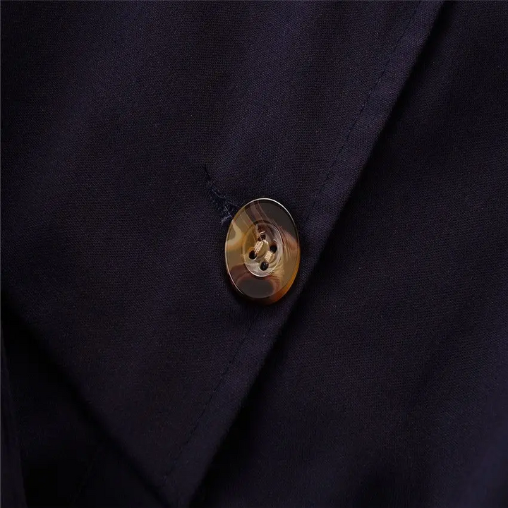 Close-up of a marbled brown button on the navy romper