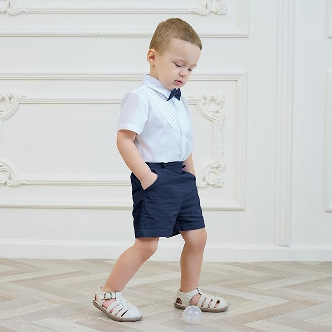 Boy walking in navy shorts, a white short-sleeve shirt, and a navy bow tie